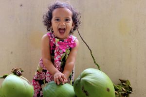 Leighanna joyously playing among the fresh coconuts.